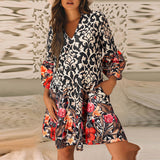 Woman wearing a boho-style long sleeve dress with ivory patterns and colorful floral print, standing in a cozy indoor setting.